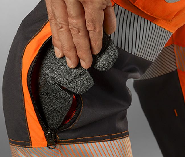 A man places a knee pad in the knee pad pocket of the high-visibility trousers.